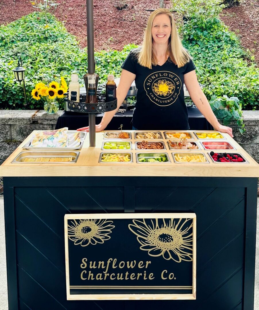 A woman standing next to a table with food on it.